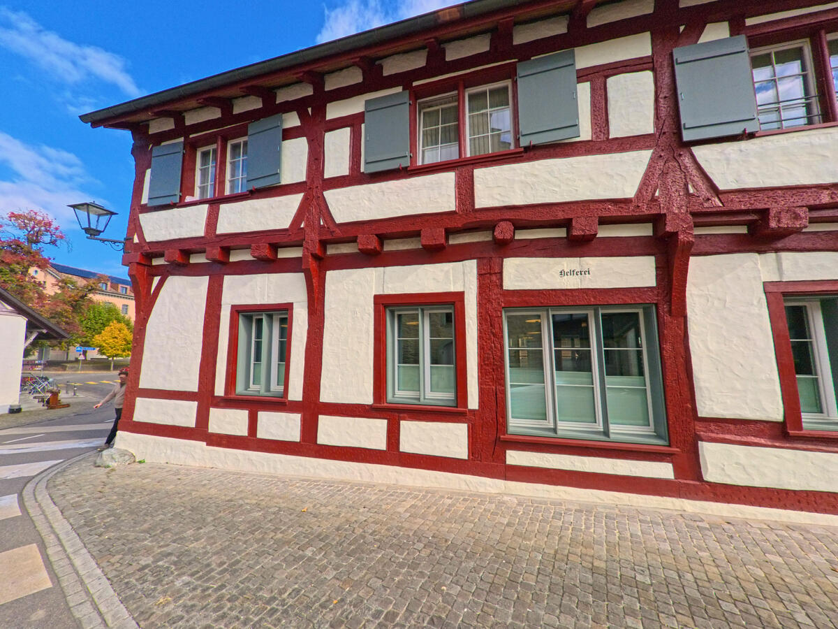 Ein rot-weiss gestrichenes Fachwerkhaus steht frei an einem gepflasterten Platz in Stein am Rhein (8260, Kanton Schaffhausen).