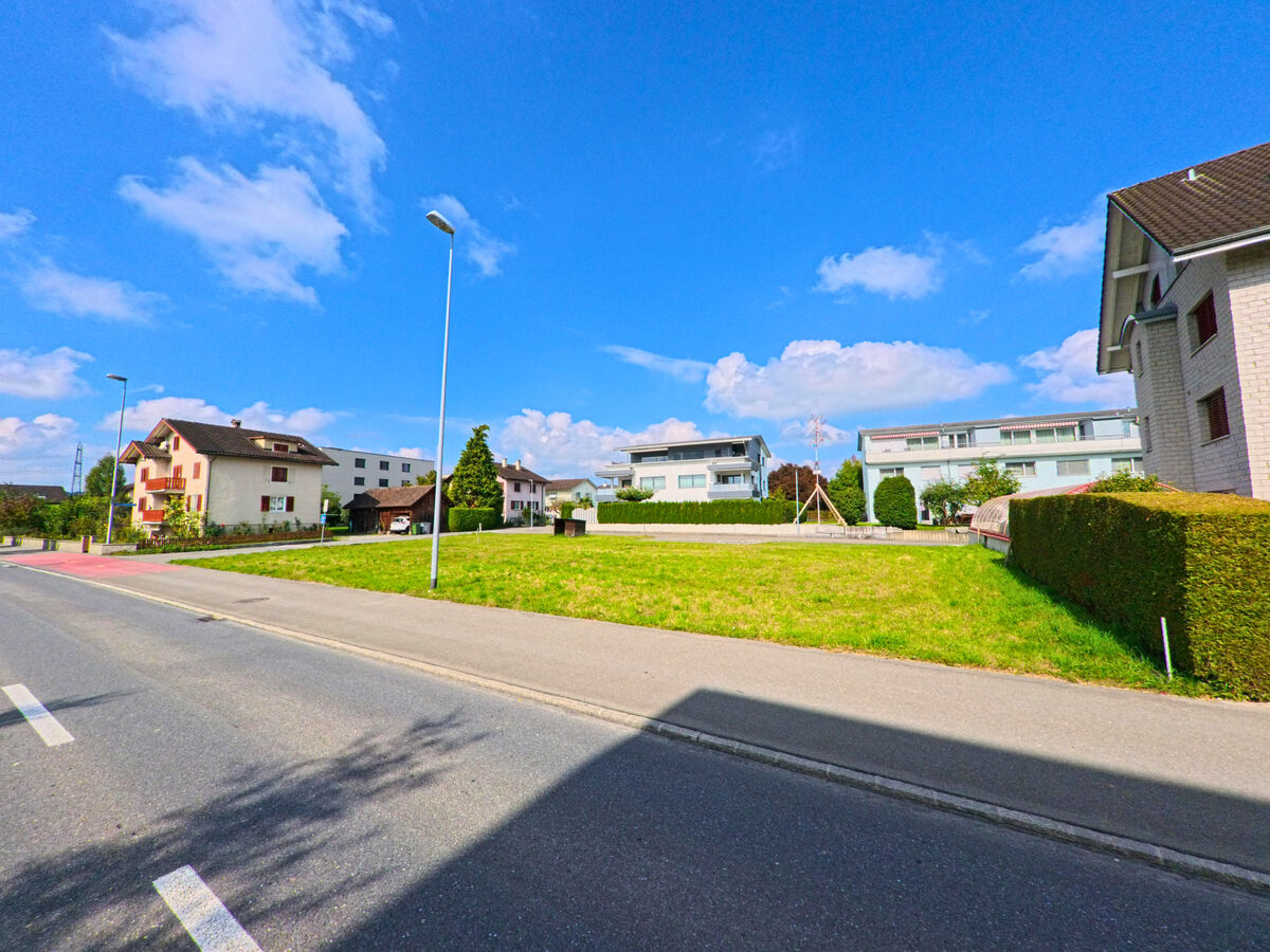 Zwischen Fahrbahn und Wohnbauten erstreckt sich eine offene Grünfläche in Inwil (6034, Kanton Luzern).