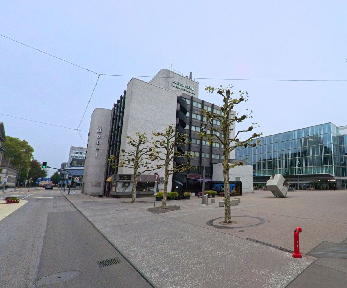 In Aarau (5000, Kanton Aargau) prägen moderne Bürogebäude, ein Hotel und junge Bäume den Platz vor dem Bahnhof.