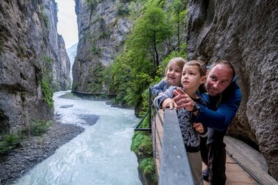 In der Aareschlucht bei Meiringen (3860, Kanton Bern) betrachten ein Mann und zwei Kinder den Fluss zwischen den hohen Felswänden.