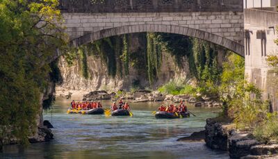 In Untersiggenthal (5417, Kanton Aargau) fahren mehrere Gruppen mit Schlauchbooten unter einer steinernen Bruecke auf dem ruhig fliessenden Fluss.