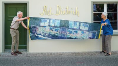 Das Adolf Dietrich-Haus in Kreuzlingen (8280, Kanton Thurgau) widmet sich dem Maler Adolf Dietrich und zeigt an der Fassade eine Enthuellungsszene mit Bildmotiv.