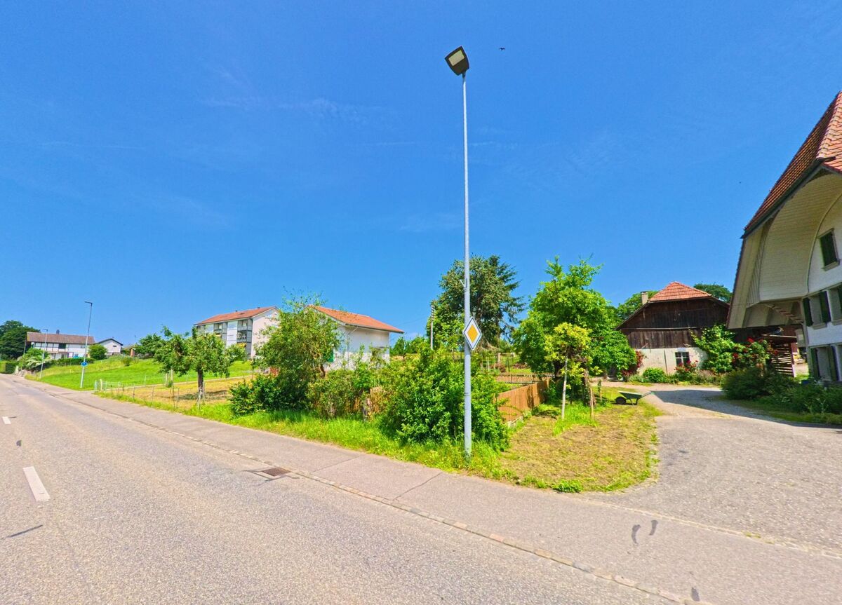 In Aeschi (4556, Kanton Solothurn) treffen moderne Wohnhaeuser und traditionelle Bauernhaeuser an einer Hauptstrasse mit Vorfahrtsschilderung aufeinander.