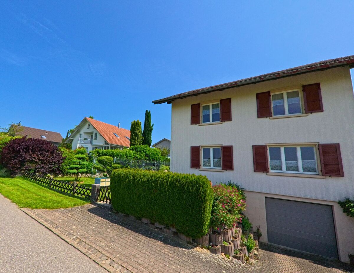 In Aeschi (4556, Kanton Solothurn) stehen gepflegte Einfamilienhaeuser mit Gaerten und roten Fensterlaeden an einer ruhig gelegenen Wohnstrasse mit leichter Steigung.