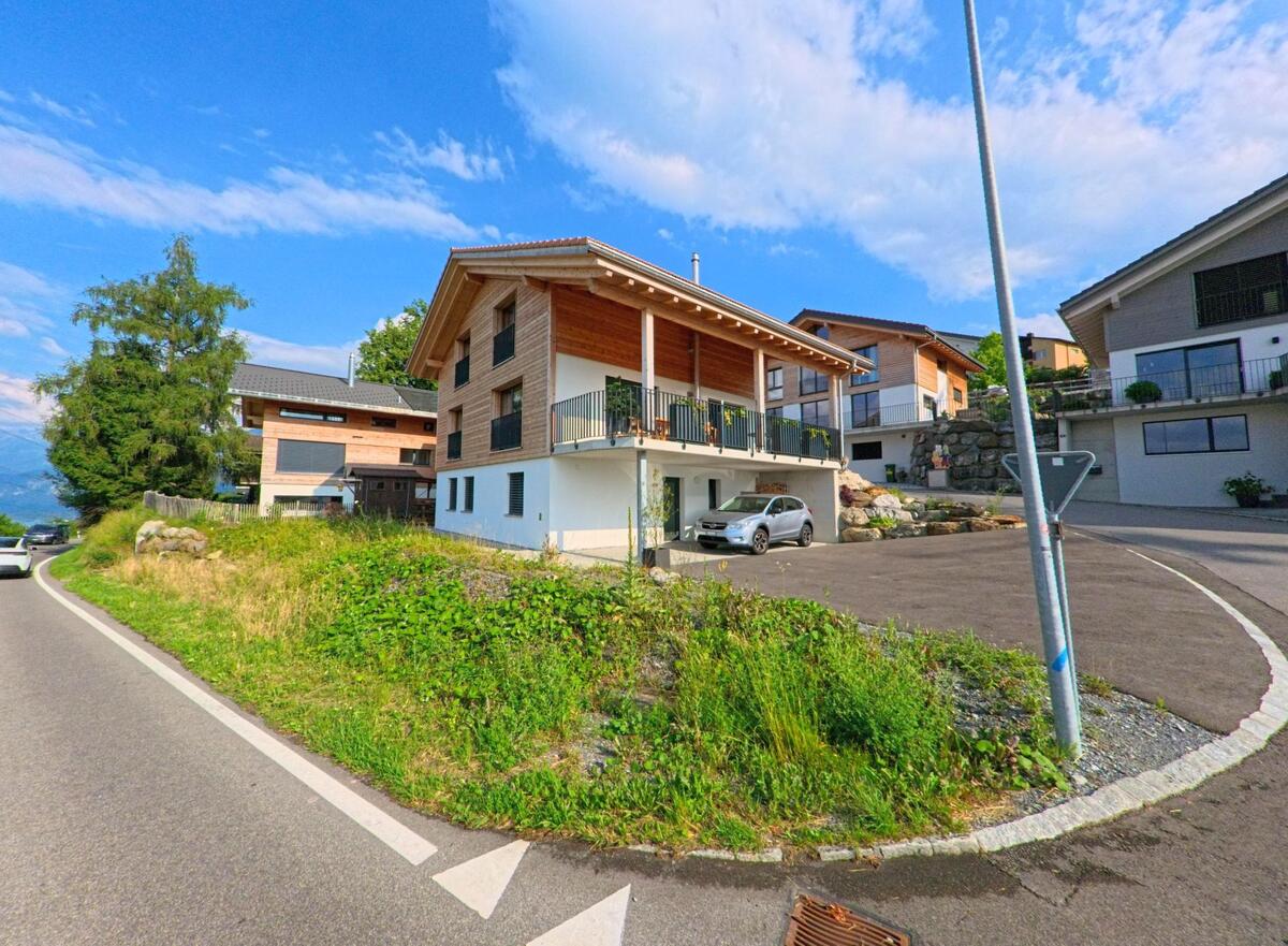 In Aeschi bei Spiez (3703, Kanton Bern) stehen moderne Einfamilienhäuser mit Holzfassaden entlang einer kurvigen Hangstrasse mit Blick ins Alpenvorland.