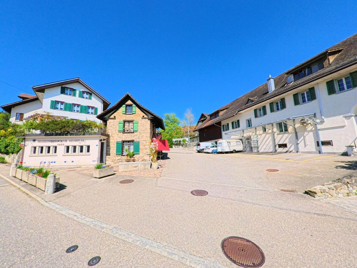 Im Zentrum von Aeugst am Albis, PLZ 8914 im Kanton Zürich, stehen ein Gebäude der Wasserversorgung von 1953, ein Natursteinhaus mit rotem Vordach und angrenzende Wohnhäuser mit grünen Fensterläden.