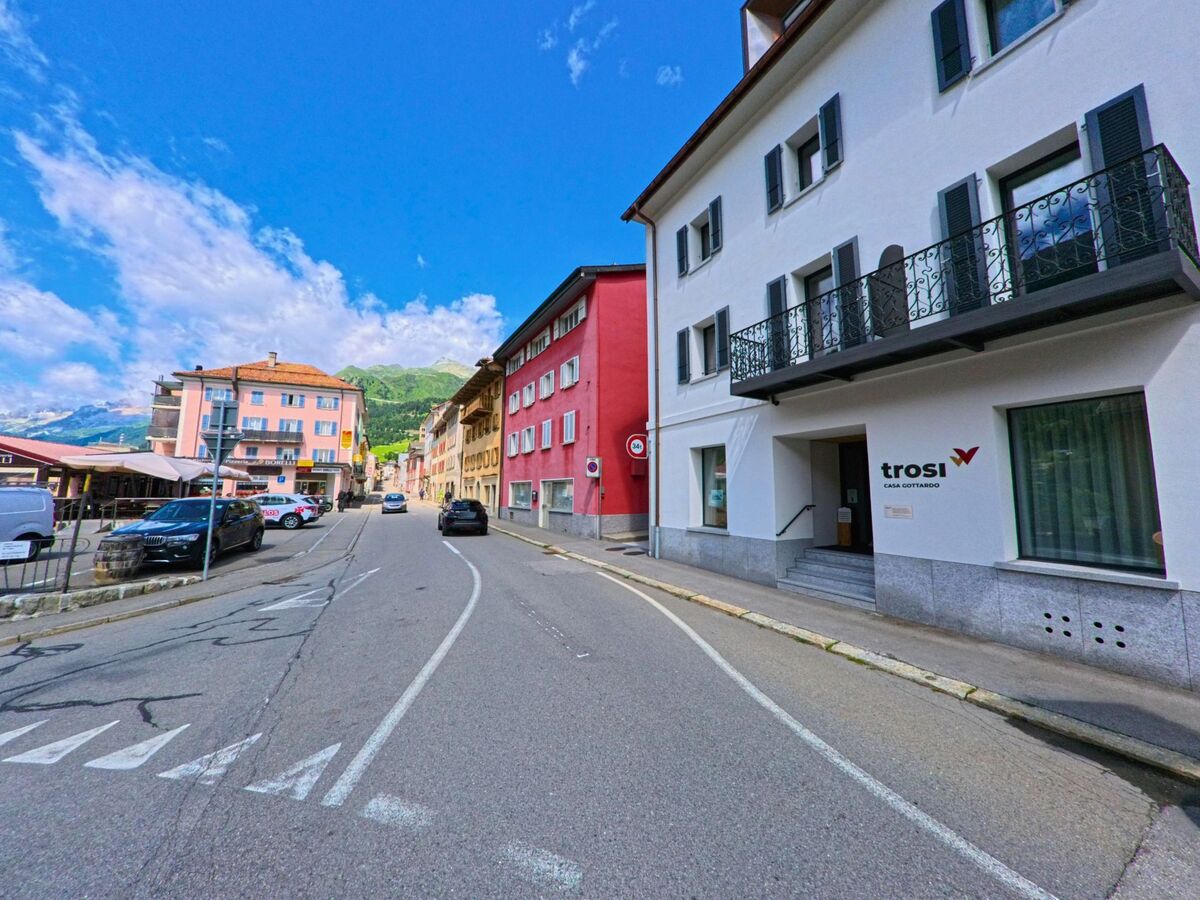 Entlang der Hauptstrasse in Airolo (6780, Kanton Tessin) stehen farbige Wohn- und Geschäftsgebäude, darunter die Casa Gottardo mit dem Schriftzug „trosi“.