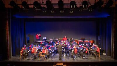 Das Akkordeon-Orchester Brittnau (Kanton Aargau) tritt auf einer Bühne in festlicher Beleuchtung unter der Leitung eines Dirigenten auf.