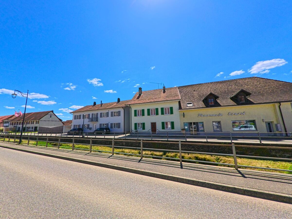In Alle (2942, Kanton Jura) reihen sich entlang einer Strasse mehrere Wohnhäuser und ein Apothekengebäude mit dem Schriftzug „Pharmacie Erard“.