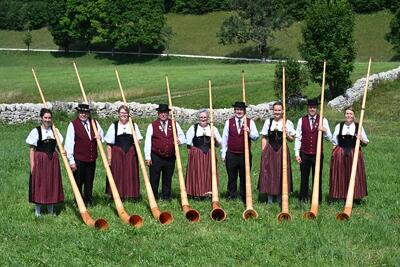 Die Mitglieder der Alphorngruppe Laupersdorf stehen in traditioneller Tracht mit ihren Alphörnern auf einer Wiese in Laupersdorf (4712, Kanton Solothurn).