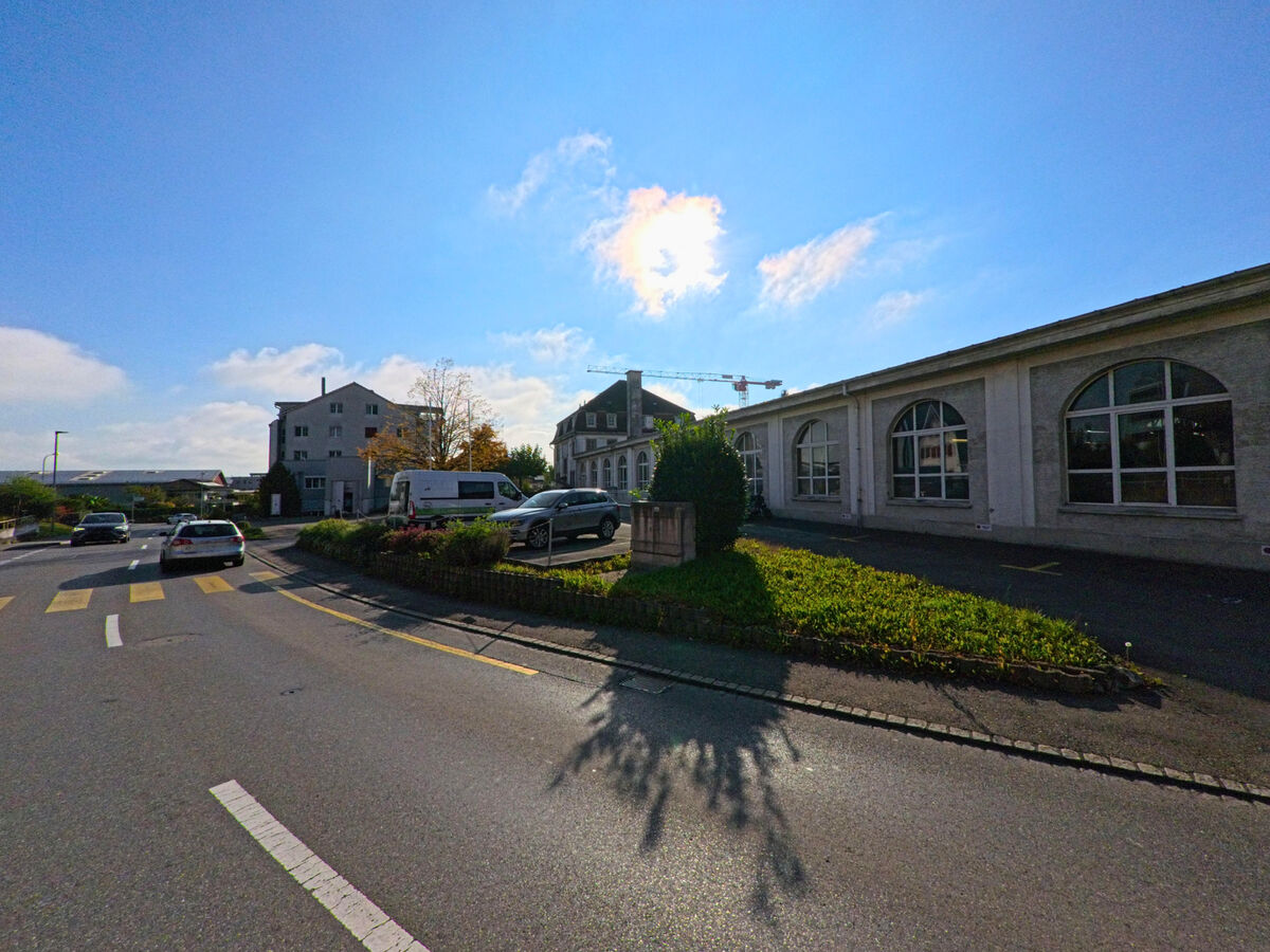 Eine Strassenszene mit flacher Bebauung und parkenden Fahrzeugen zeigt den Alltag in Altstaetten (9450, Kanton St. Gallen).