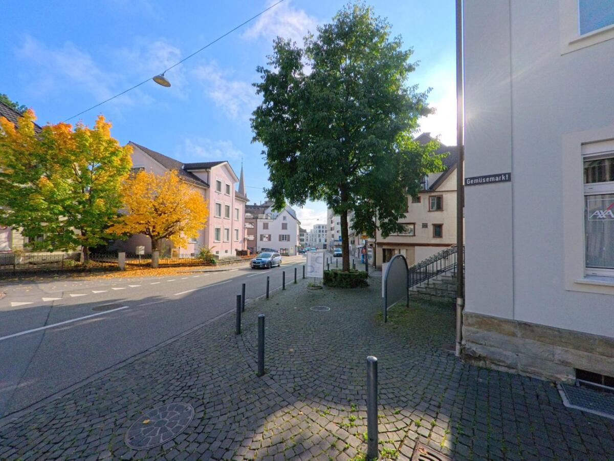 Entlang einer ruhigen Strasse in Altstätten (9450, Kanton St. Gallen) stehen bunte Häuser und Bäume, deren Herbstlaub über dem Trottoir leuchtet.