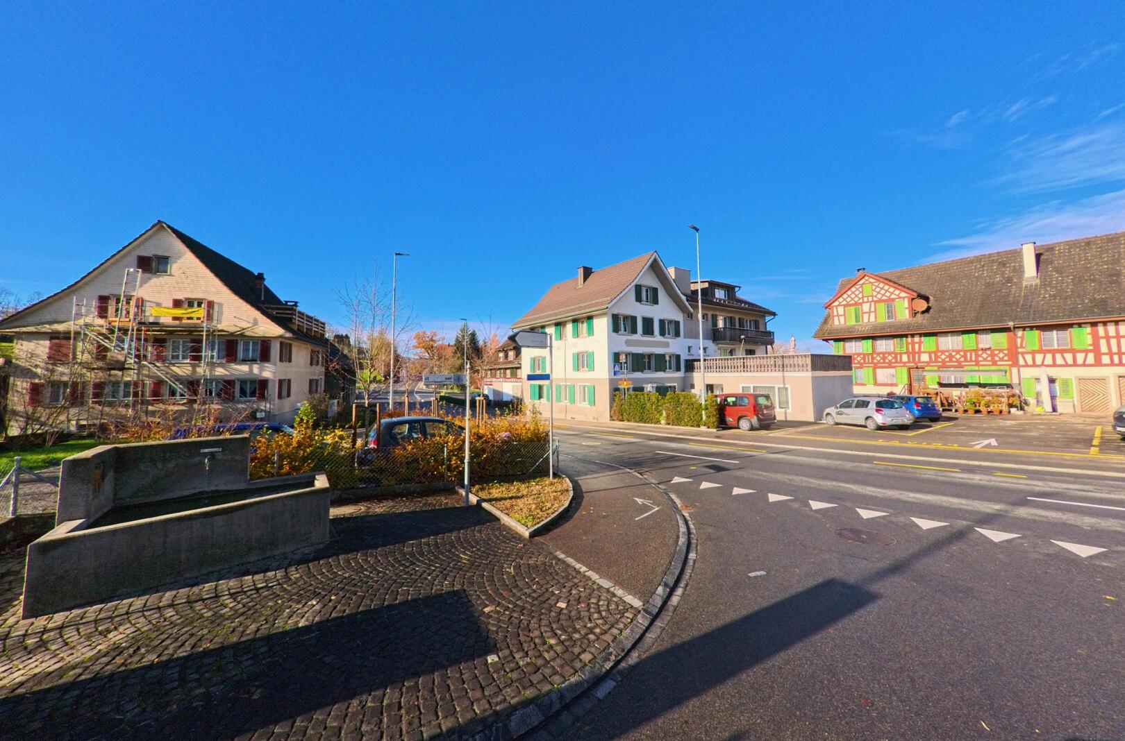An einer Strassenkreuzung mit historischen Wohnhaeusern praegt das Dorfzentrum von Amlikon-Bissegg (8514, Kanton Thurgau) das Ortsbild bei klarem Himmel.