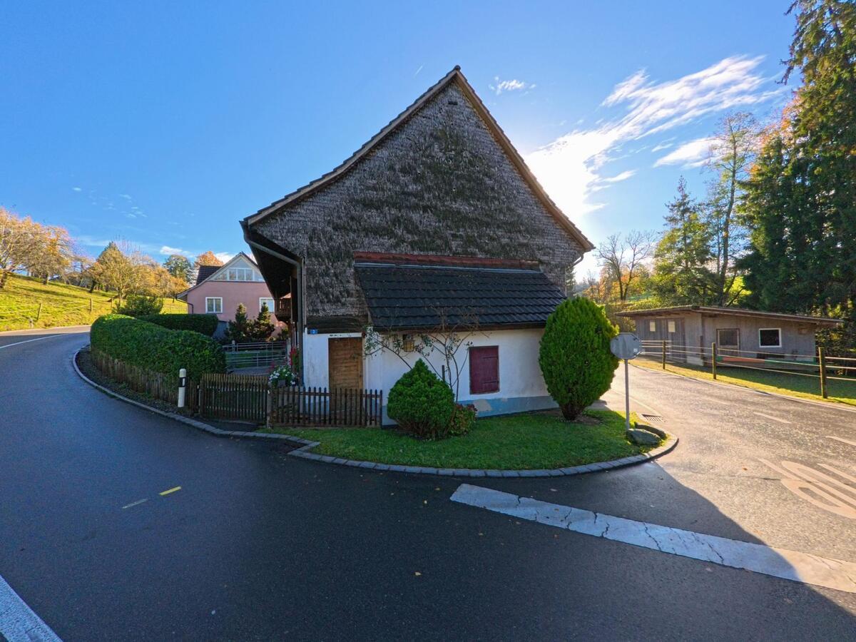 An einer sanft geschwungenen Strasse steht ein traditionelles Wohnhaus mit Holzfassade in Amlikon-Bissegg (8514, Kanton Thurgau) umgeben von gepflegtem Gruen.