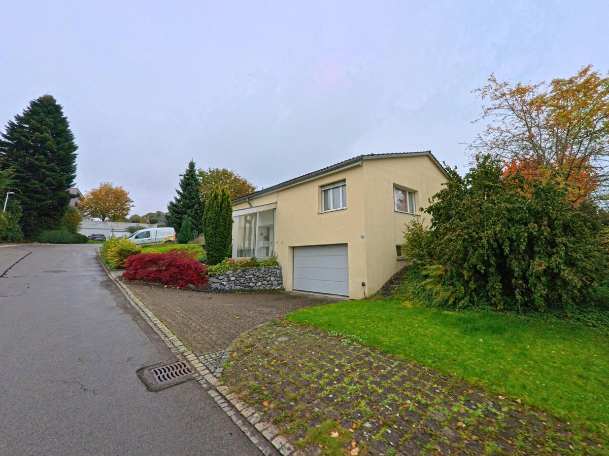 Ein Einfamilienhaus mit Garage liegt an einer leicht ansteigenden Wohnstrasse in Andwil (9212, Kanton St. Gallen).