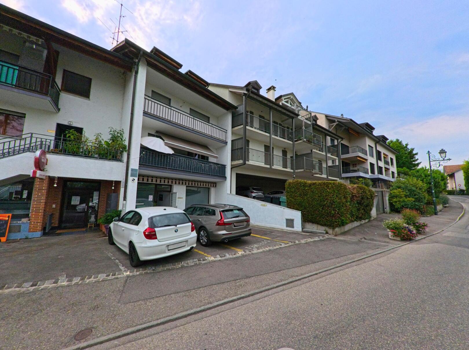 Mehrfamilienhaeuser mit Balkonen und vorgelagerten Parkplaetzen praegen das Strassenbild in Anieres (1247, Kanton Genf).