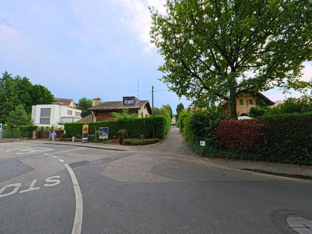 Ein schmaler Weg fuehrt zwischen Hecken und Wohnhaeusern in Anieres (1247, Kanton Genf) in ein ruhiges Quartier.