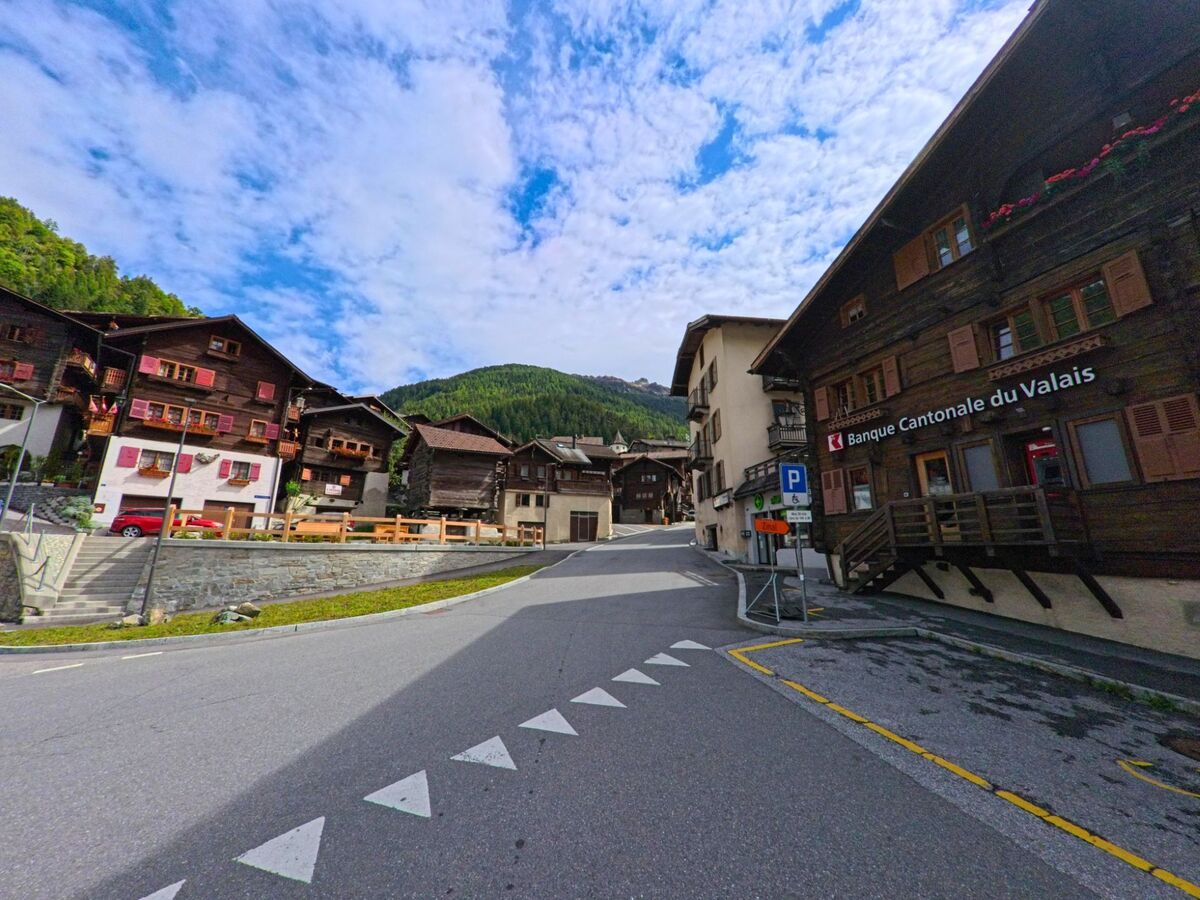 Entlang der Hauptstrasse in Anniviers (3961, Kanton Wallis) reihen sich traditionelle Holzhäuser, rechts im Bild befindet sich eine Filiale der Banque Cantonale du Valais.