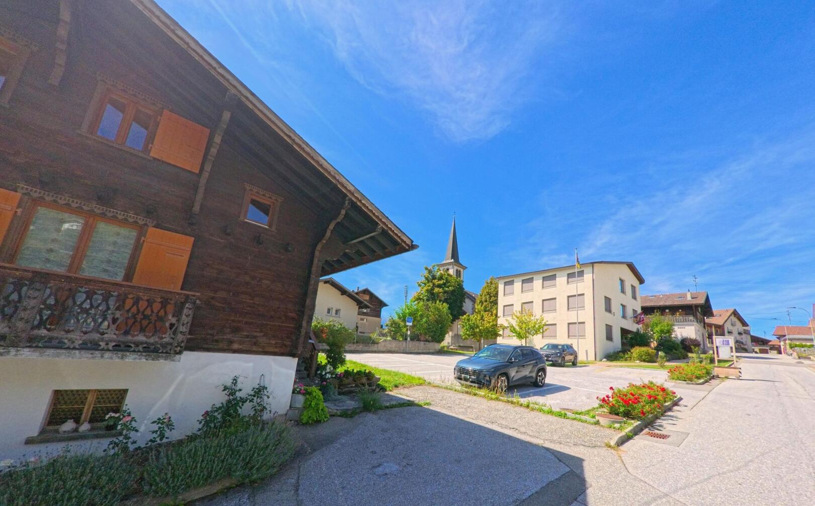 Im Zentrum von Arbaz (1974, Kanton Wallis) steht eine Kirche mit hohem Turm, umgeben von traditionellen Wohnhaeusern und gepflegten Plaetzen.