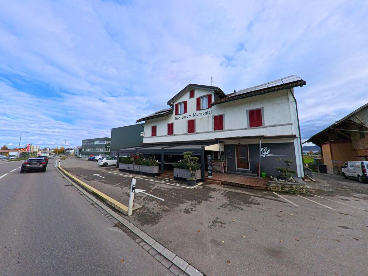 An einer Hauptstrasse in Arbon (9320, Kanton Thurgau) steht ein traditionelles Gebaeude mit Gastronomiebereich und Parkplaetzen vor dem Haus.