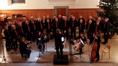 In einer Kirche singen die Arboner Saenger in Arbon (9320, Kanton Thurgau) gemeinsam mit einem Streichensemble waehrend eines Konzerts unter der Leitung eines Dirigenten.