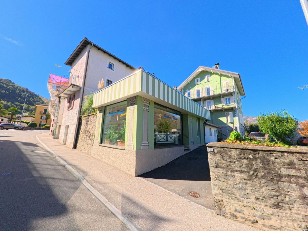 In Arcegno (6616, Kanton Tessin) reihen sich farbige Haeuser mit kleinen Geschaeften entlang einer ansteigenden Strasse.