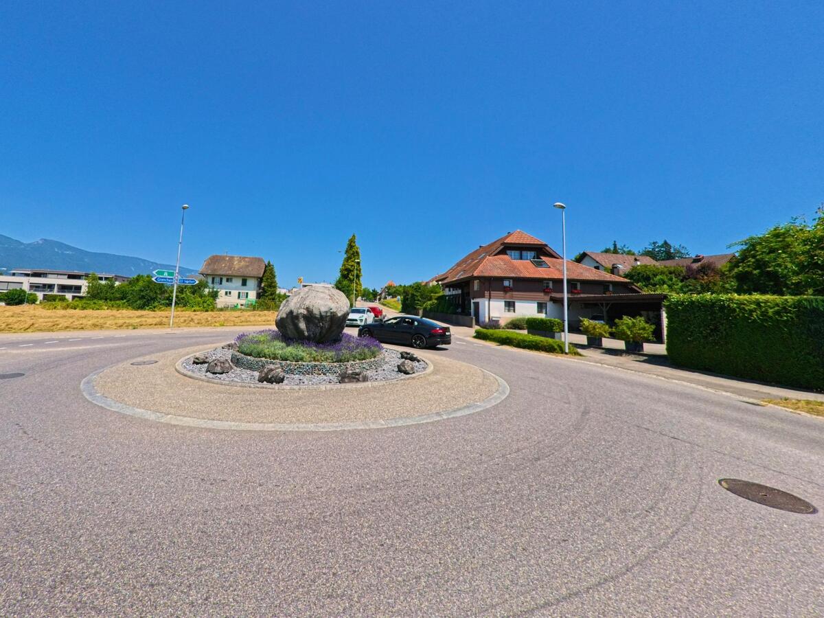 In Arch (3296, Kanton Bern) markiert ein gepflegter Kreisverkehr mit einem grossen Findling in der Mitte den Übergang zwischen Wohnquartier und Ausfallstrasse.