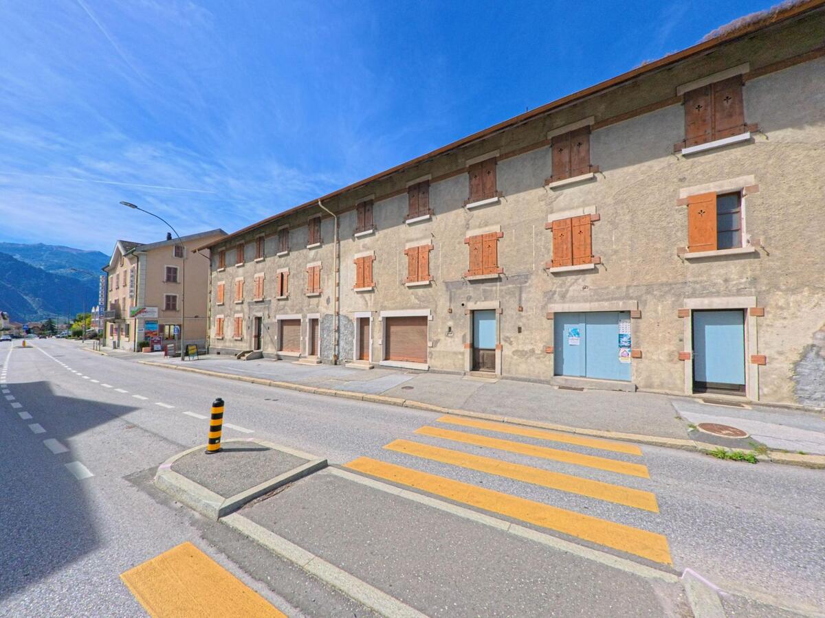 An der Hauptstrasse in Ardon (1957, Kanton Wallis) stehen traditionelle Haeuser mit geschlossenen Fensterlaeden und Laeden im Erdgeschoss.