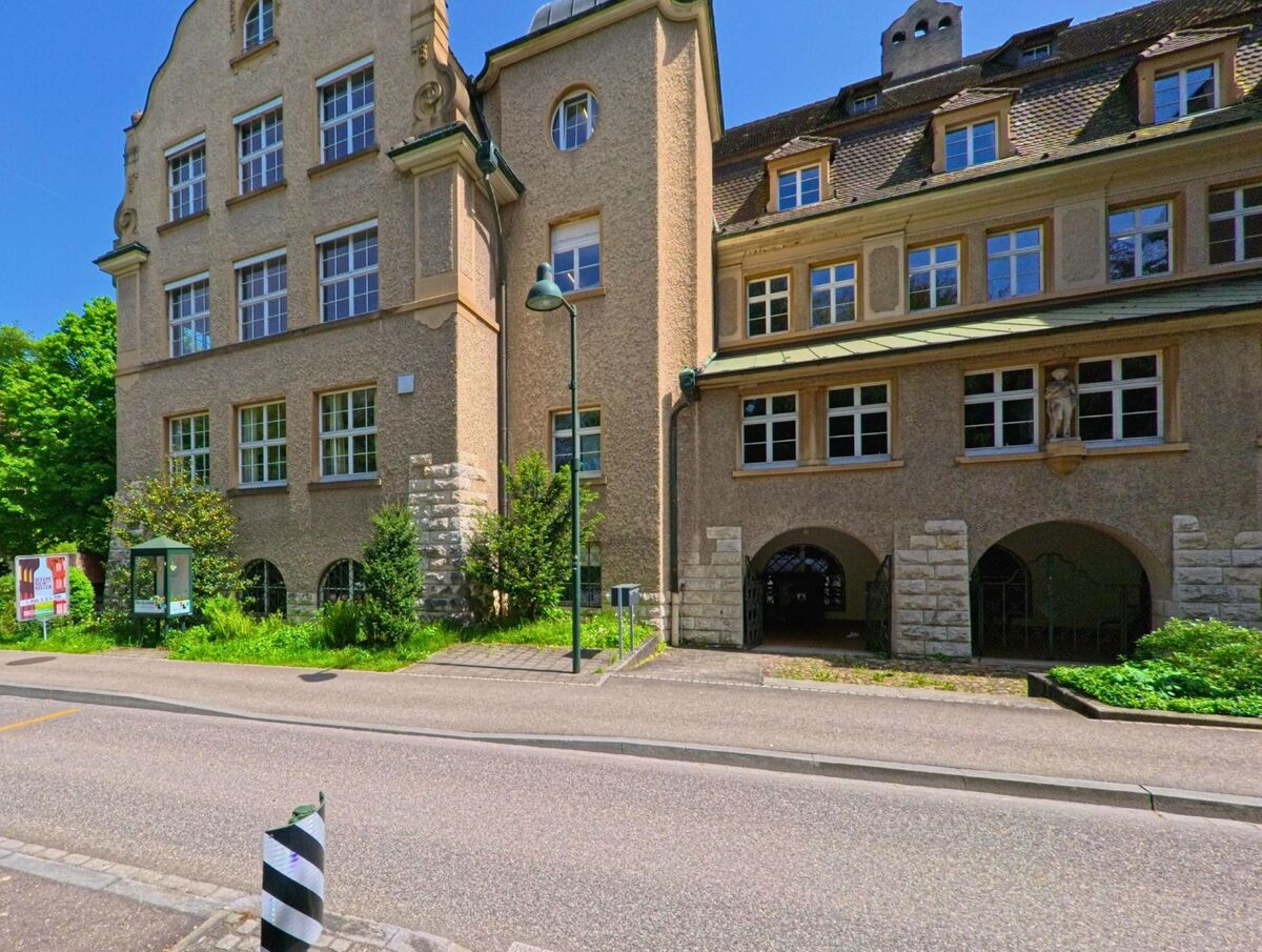 In Arlesheim (4144, Kanton Basel-Landschaft) steht ein imposantes Gebäude mit Rundbögen und historischen Fassadenelementen direkt an der Strasse.