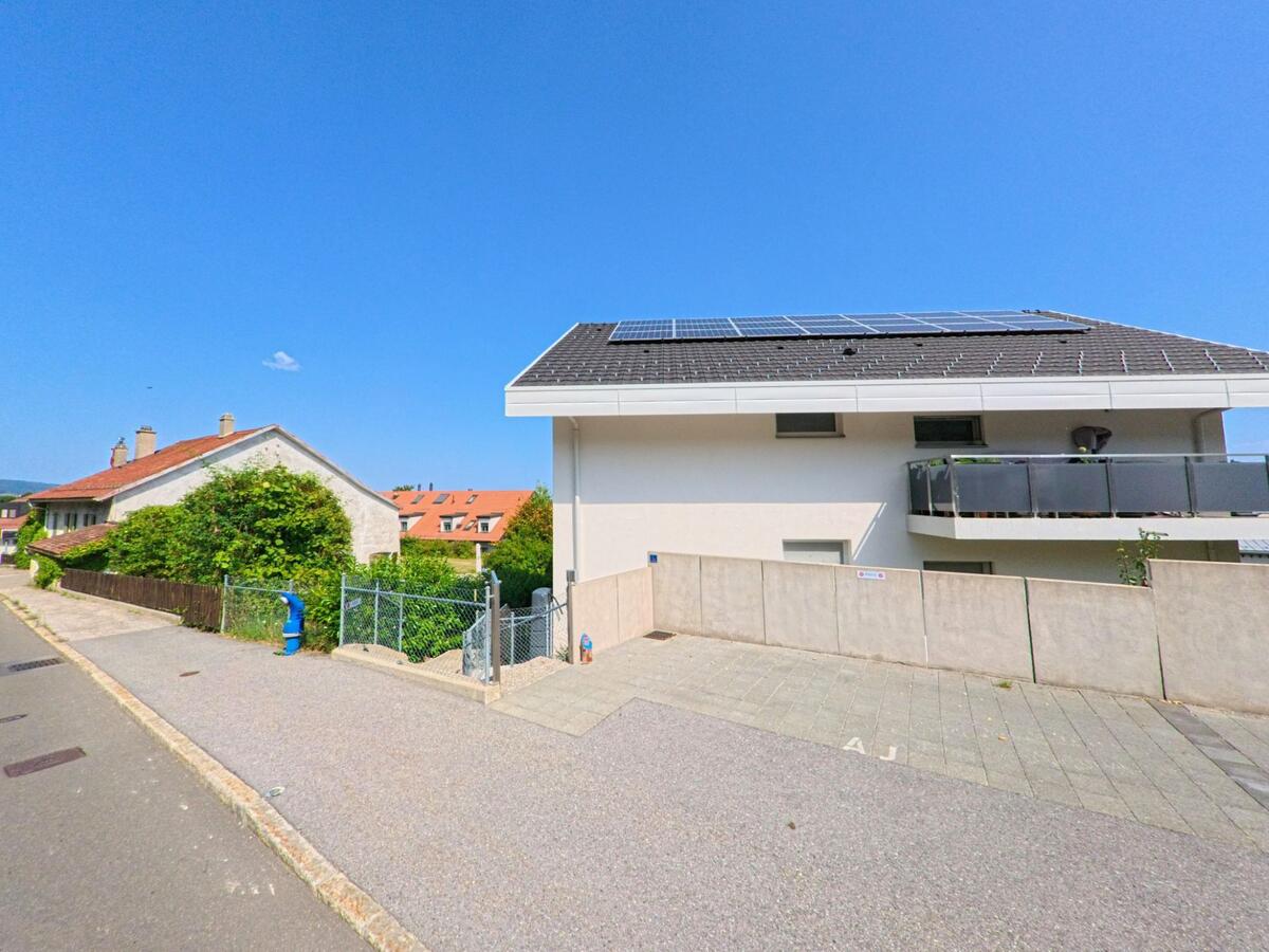 Ein modernes Wohnhaus mit Solaranlage auf dem Dach steht in Arzier-Le Muids (1273, Kanton Waadt) neben aelteren Gebaeuden.