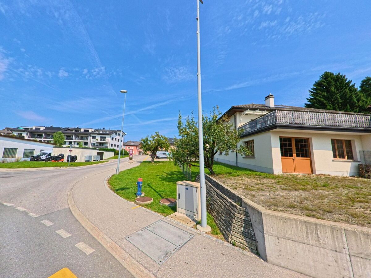 An einer leicht ansteigenden Strasse in Attalens (1616, Kanton Freiburg) stehen Einfamilienhäuser und moderne Mehrfamilienbauten.