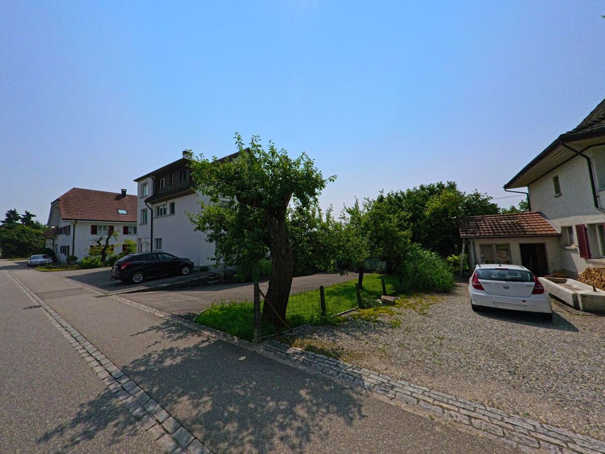 In einem ruhigen Wohngebiet von Attiswil (4536, Kanton Bern) stehen Ein- und Mehrfamilienhäuser entlang einer asphaltierten Strasse mit Parkplätzen und gepflegten Vorgärten.