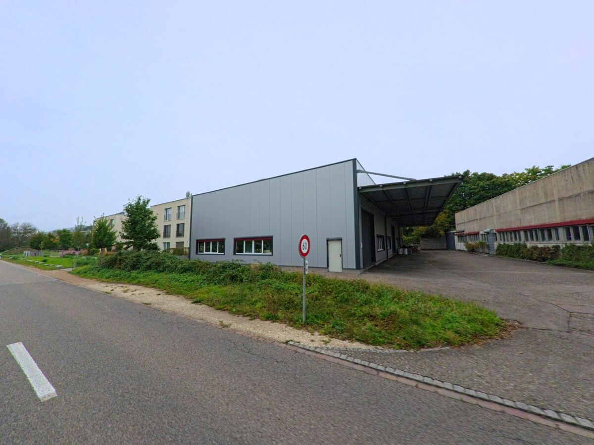 Ein modernes Industriegebäude mit grauer Fassade und überdachtem Ladebereich steht an der Hauptstrasse in Auenstein (5105, Kanton Aargau).