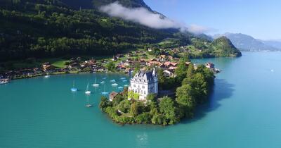 In Interlaken (3800, Kanton Bern) liegt das Schloss am Ufer des Brienzersees bei Boenigen-Iseltwald, umgeben von smaragdgruem Wasser und malerischen Haeusern.