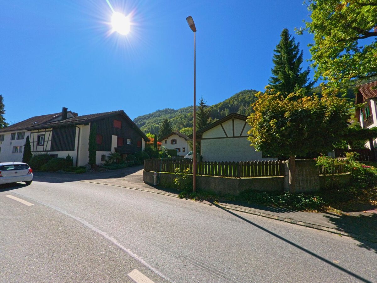 In Bad Ragaz (7310, Kanton St. Gallen) stehen Einfamilienhäuser mit Gärten an einer sonnigen Strasse, umgeben von grünen Hügeln und klarer Bergluft.