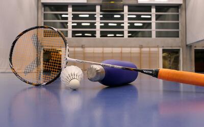 Ein Badmintonschlaeger und Shuttlecocks liegen auf dem Boden einer Turnhalle in Murten (3280, Kanton Freiburg) und zeigen Hallensport.