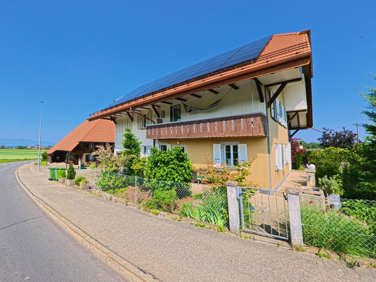 Am Ortsrand von Bätterkinden (3315, Kanton Bern) steht ein gepflegtes Haus mit Solaranlage auf dem Dach und blühendem Vorgarten an einer leicht geschwungenen Strasse.