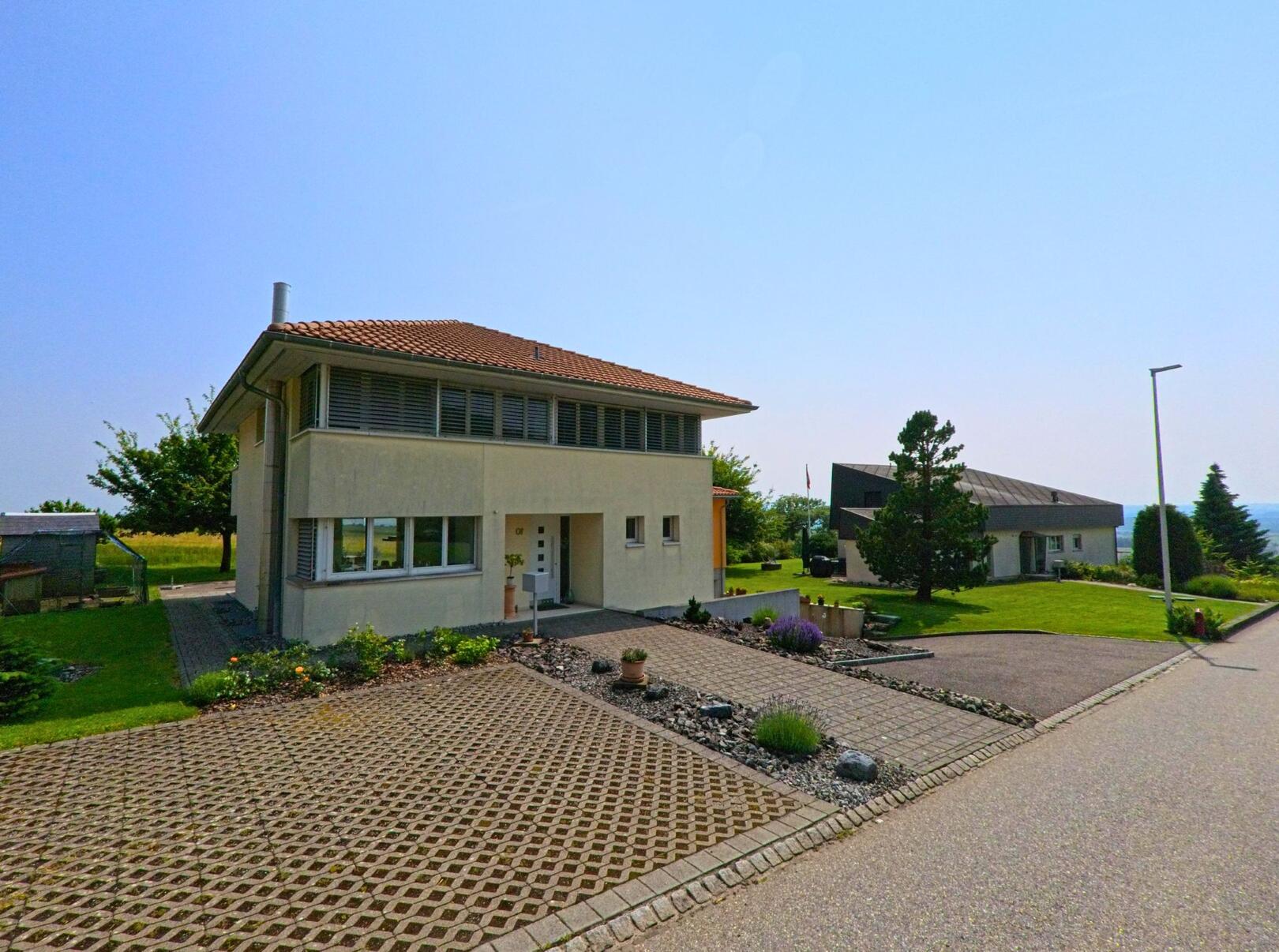 In Balm bei Günsberg (4525, Kanton Solothurn) steht ein modernes Haus an einer ruhigen Strasse, umgeben von gepflegten Gärten und einer weiten Aussicht auf die Landschaft.