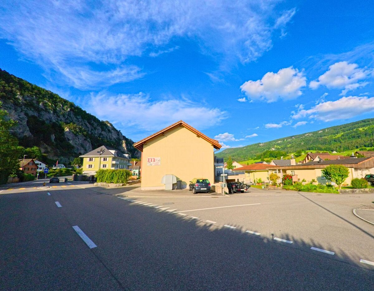 In Balsthal im Kanton Solothurn, PLZ 4710, befindet sich ein kleines Gewerbegebäude an einer Einmündung, umgeben von Wohnhäusern und mit Blick auf bewaldete Hügel.