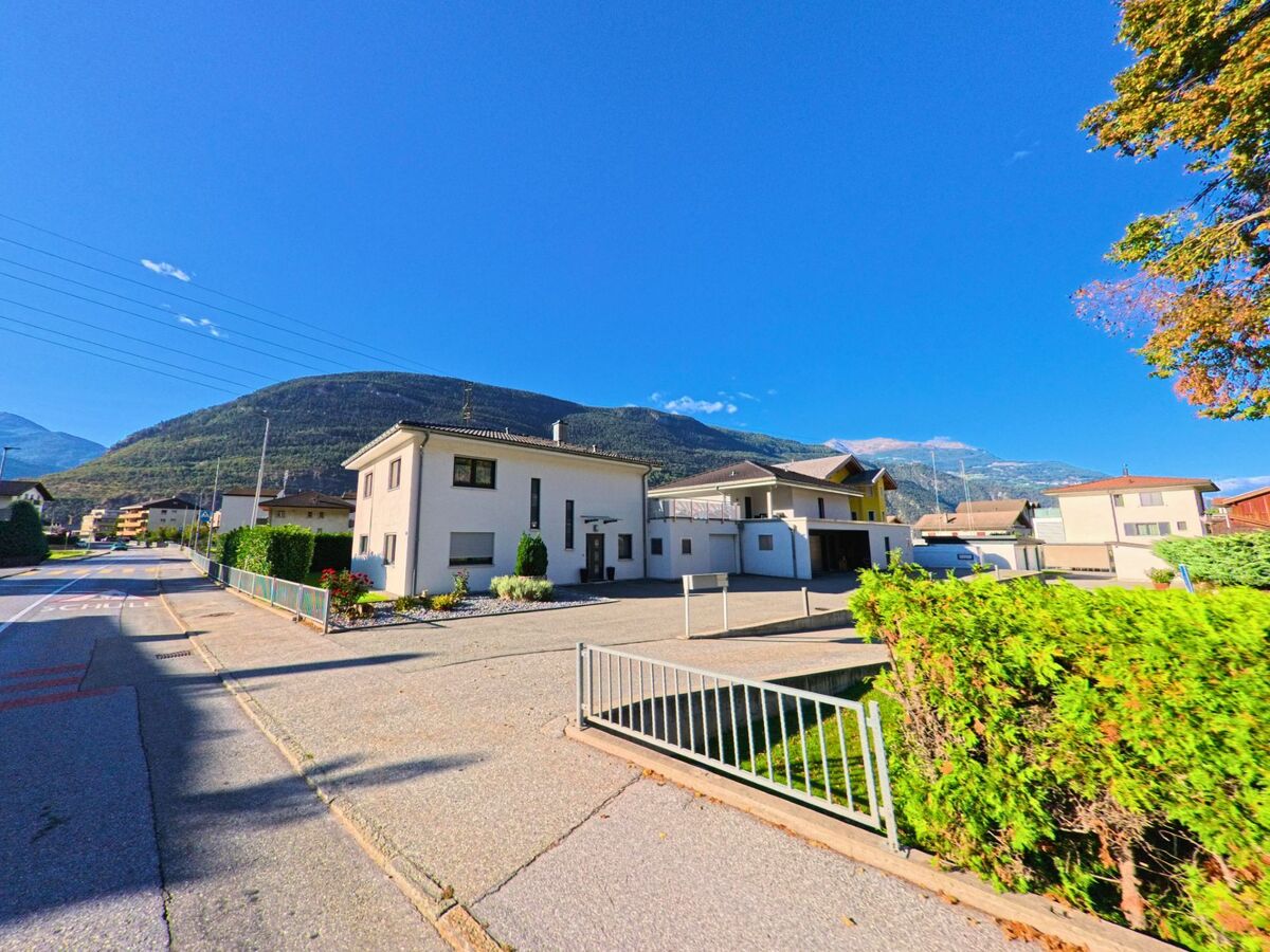 Entlang einer Strasse in Baltschieder (3937, Kanton Wallis) stehen moderne Einfamilienhaeuser mit gepflegten Gaerten und Blick auf die Berge.