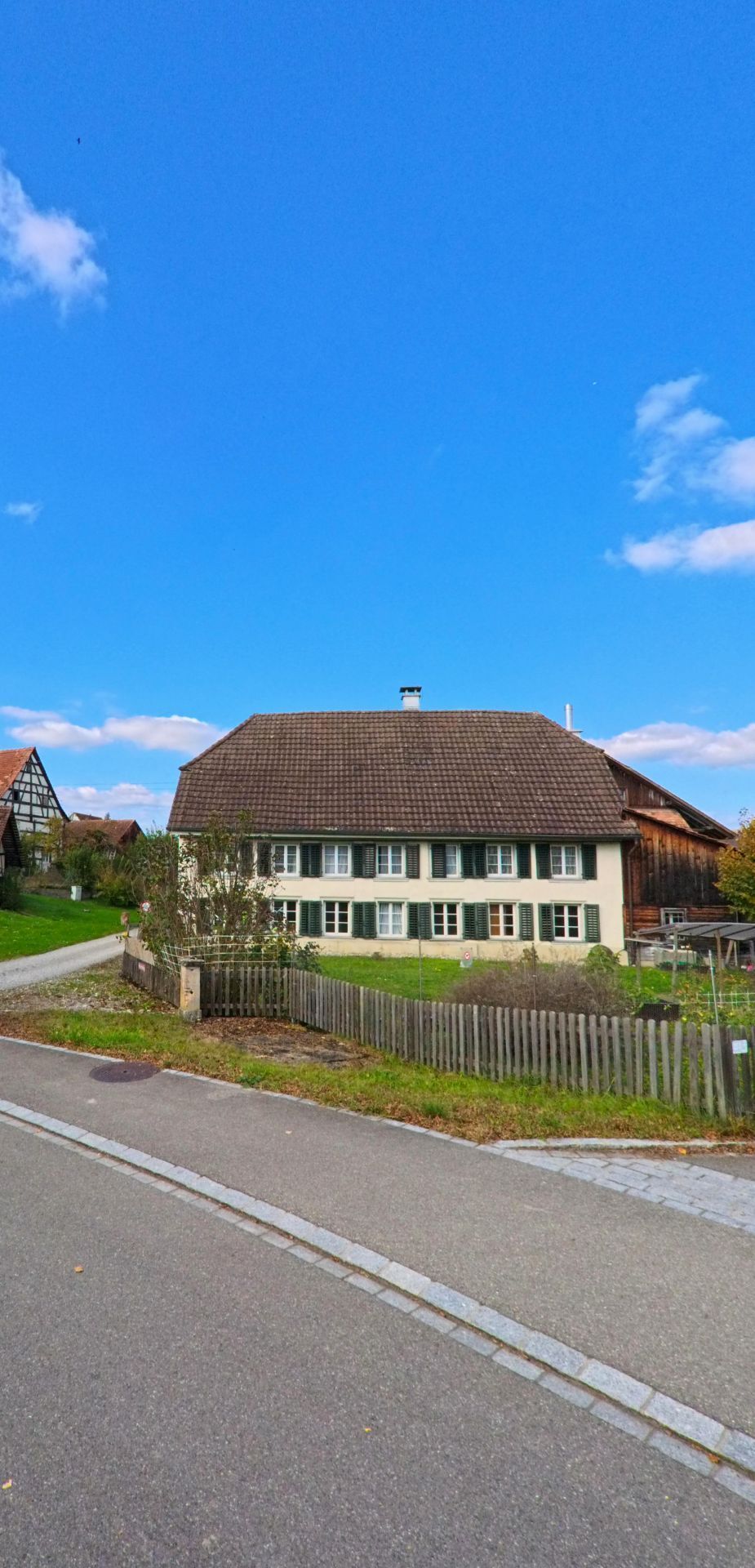 Ein freistehendes Wohnhaus mit gepflegtem Garten steht an einer ruhigen Strasse in Basadingen-Schlattingen (8254) im Kanton Thurgau vor weitem Himmel.