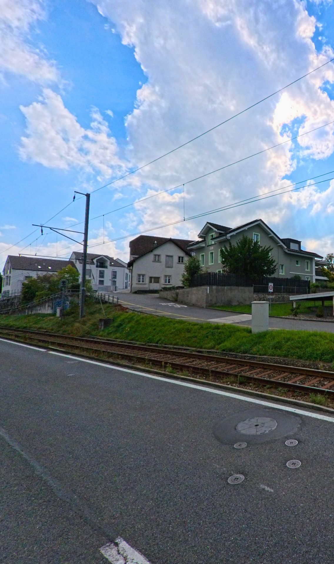 Mehrere Wohnhäuser stehen oberhalb der Bahnlinie in Beinwil am See (5712, Kanton Aargau), mit Zufahrtswegen und begrünten Böschungen entlang der Strasse.