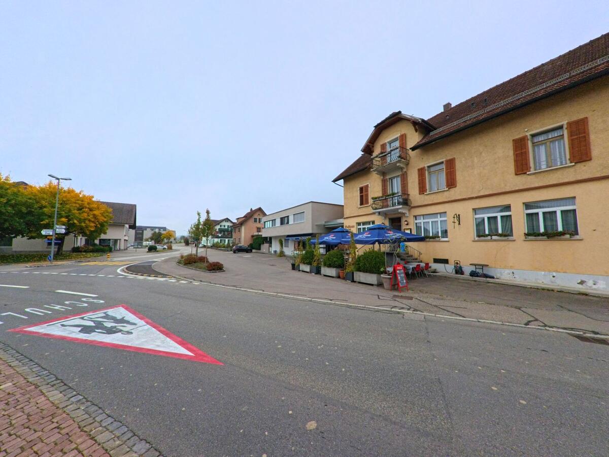An der Hauptstrasse in Beinwil (Freiamt, 5637, Kanton Aargau) steht ein Gasthaus mit Sonnenschirmen und kleiner Terrasse neben weiteren Wohnhaeusern.