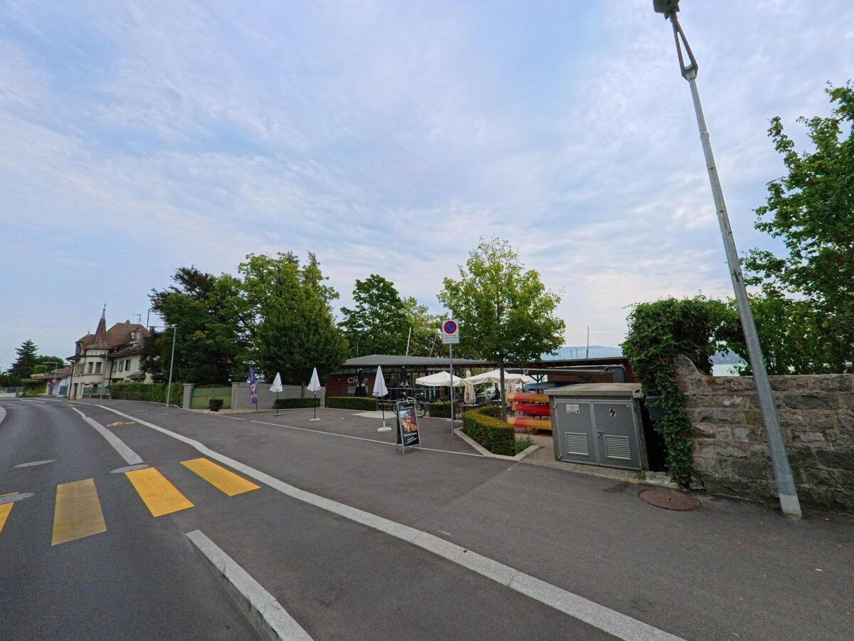 Am Ufer des Genfersees in Bellevue (1293, Kanton Genf) befindet sich ein kleiner Hafenbereich mit Restaurantterrasse und Booten hinter einer Steinmauer.