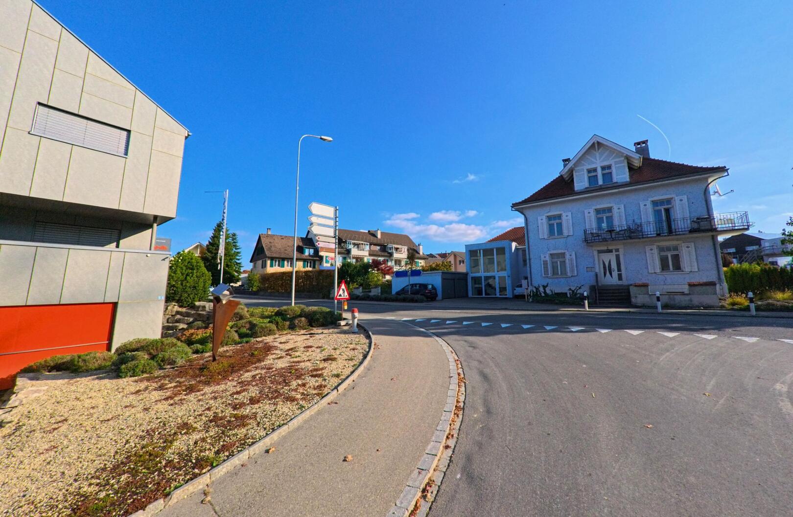 An einer übersichtlichen Kreuzung mit Wohnhäusern zeigt sich das Ortsbild von Berg (8572, Kanton Thurgau) bei klarem Himmel und ruhiger Verkehrssituation.