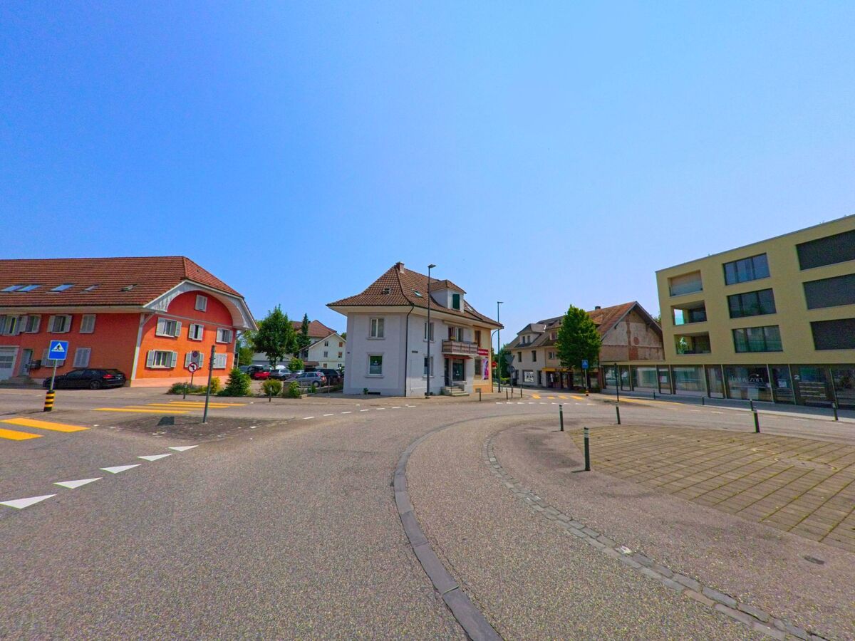  Im Zentrum von Biberist (4562, Kanton Solothurn) treffen moderne und traditionelle Gebäude an einem kleinen Strassenplatz mit Verkehrsinsel und Zebrastreifen aufeinander.