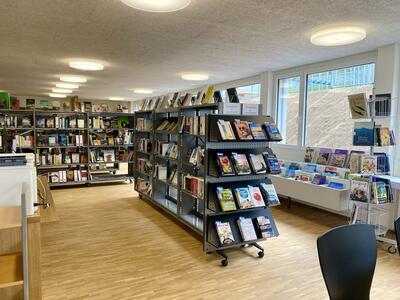 In einer hellen Bibliothek mit mehreren Bücherregalen und Auslagen stehen zahlreiche Bücher zur Auswahl in Schwellbrunn (9103, Kanton Appenzell Ausserrhoden).