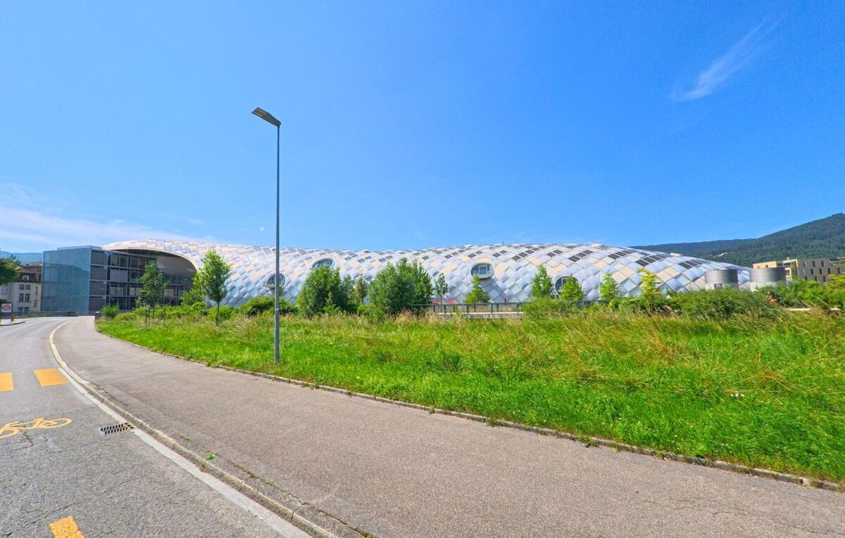 Das futuristische Gebäude in Biel/Bienne (2500, Kanton Bern) mit seiner markanten Glas- und Holzkonstruktion sticht in das Stadtbild und ist von grünen Flächen umgeben.