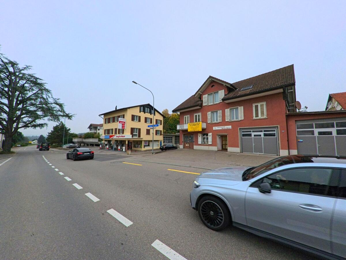 Im Zentrum von Birmenstorf (5413, Kanton Aargau) stehen entlang der Hauptstrasse Wohn- und Geschaeftshaeuser mit Läden im Erdgeschoss.