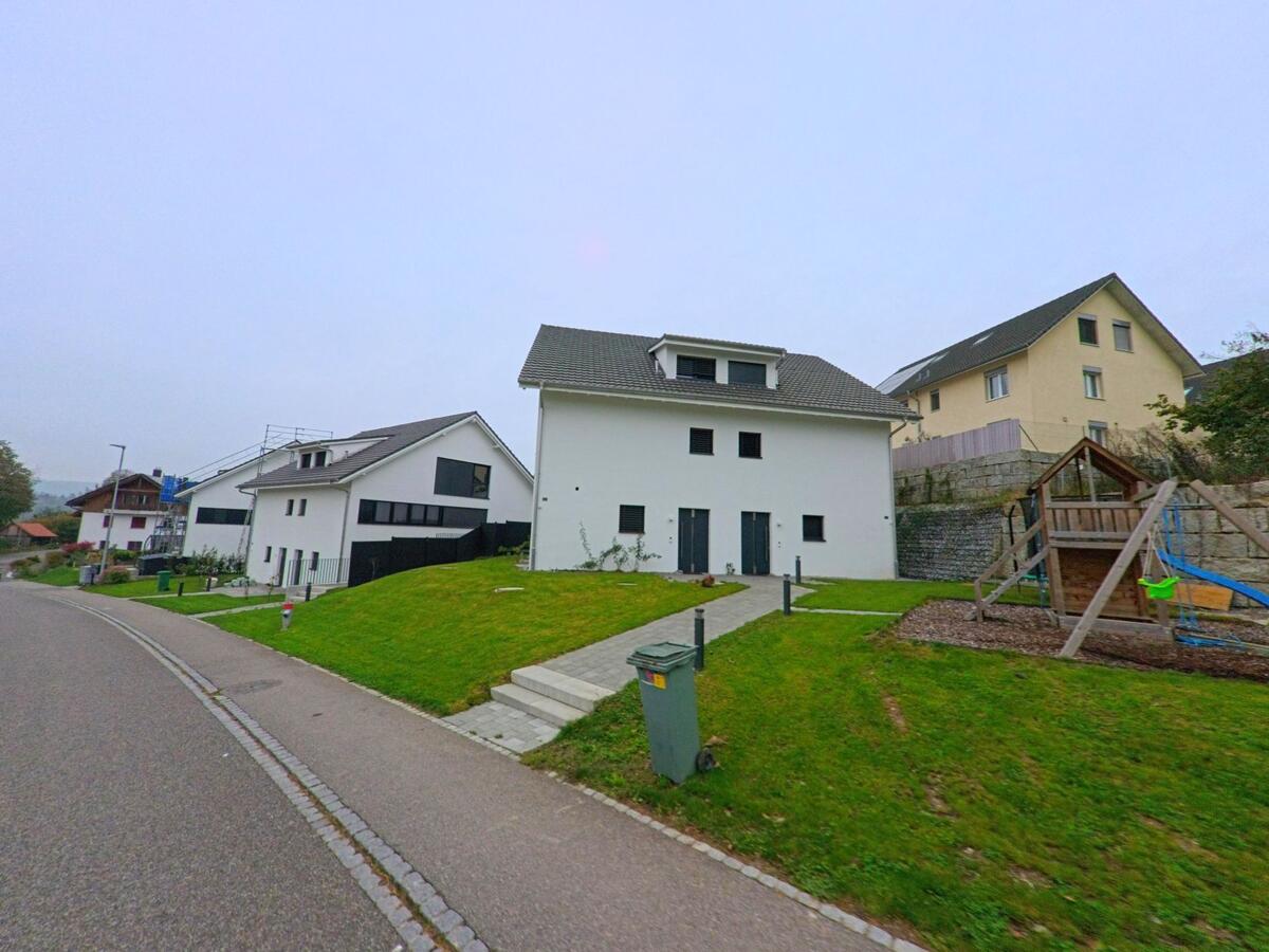 In einem neuen Wohngebiet von Birrhard (5244, Kanton Aargau) stehen moderne Einfamilienhäuser mit gepflegten Gärten und einem kleinen Spielplatz.